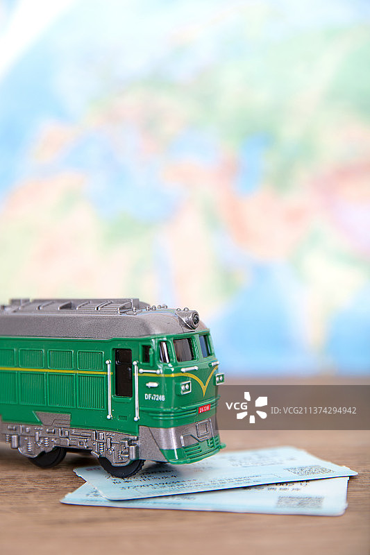 地图背景前桌子上的绿皮小火车和车票图片素材