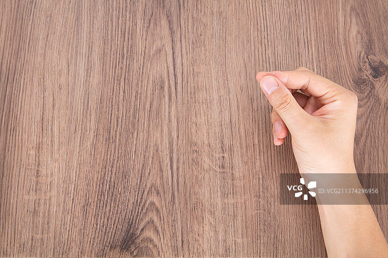 一只手在桌子上做捏着东西的手势图片素材