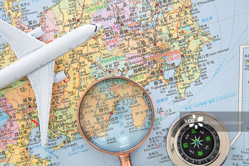 日本地图上的飞机模型和放大镜及指南针图片素材