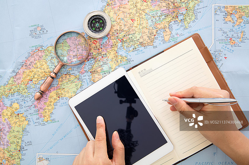 旅行者在日本地图上使用iPad和笔记本制作旅行计划图片素材