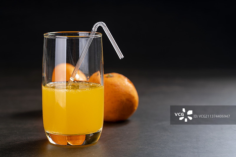橙汁与橙子摆放在黑色背景上特写图片素材