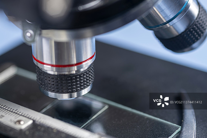 科研人员带着橡胶手套操作显微镜特写蓝色背景图片素材