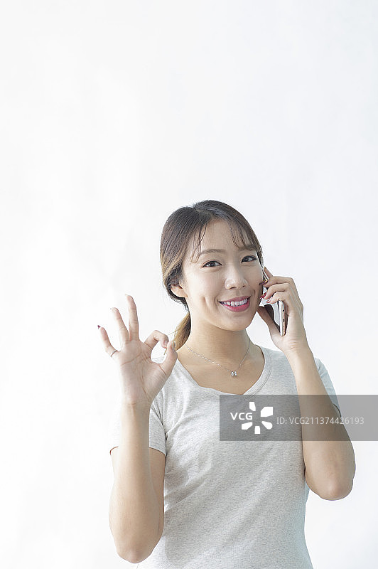 边讲电话边作同意手势的东方美女图片素材