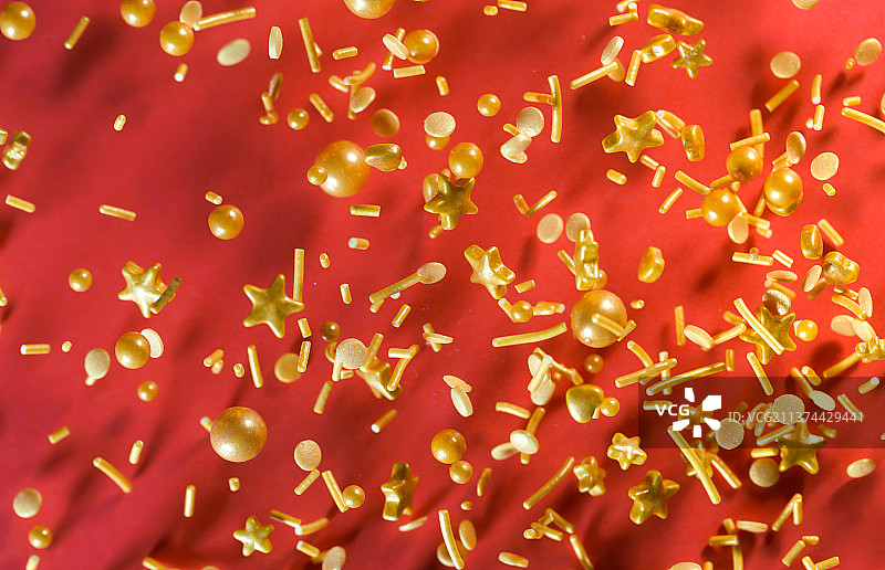 金色各类糖果掉落在红色背景上棚拍创意图图片素材