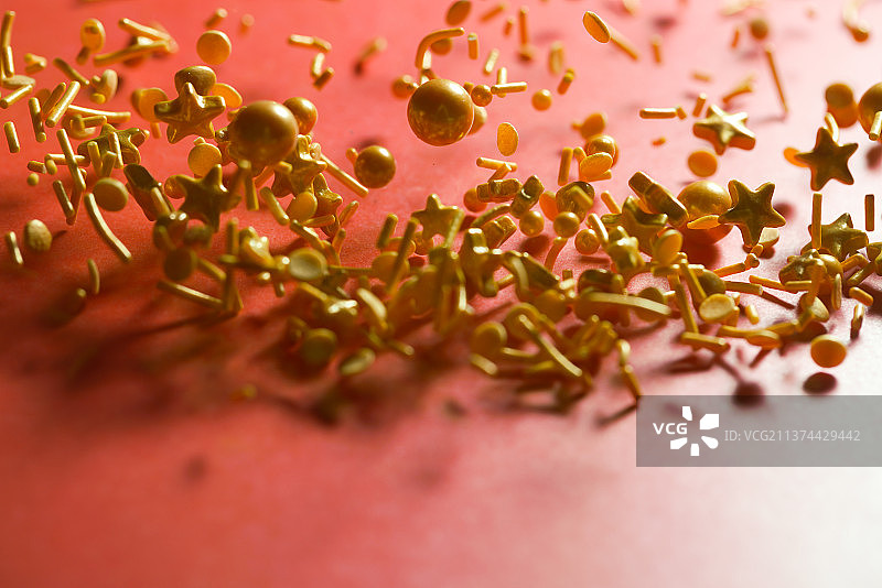 金色各类糖果掉落在红色背景上棚拍创意图图片素材