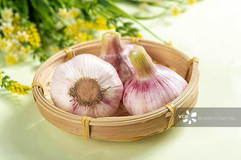 一簸箕新鲜大蒜摆放在桌面上图片素材
