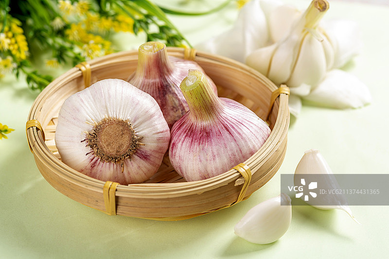 一簸箕新鲜大蒜摆放在桌面上图片素材