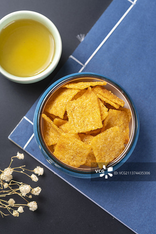 休闲零食小米锅巴与茶水摆放在桌面上特写图片素材