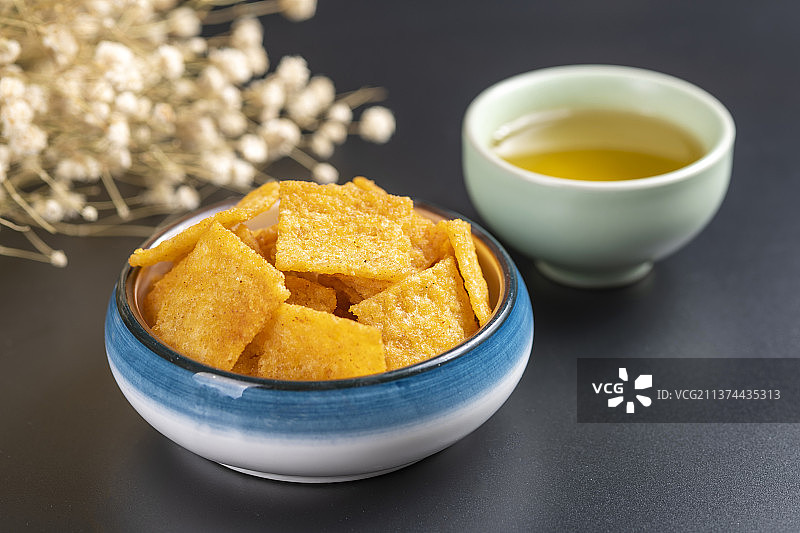 休闲零食小米锅巴与茶水摆放在桌面上特写图片素材