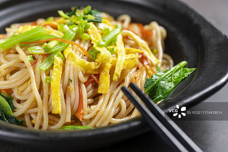 一盘快餐炒米线摆放在黑色背景上图片素材