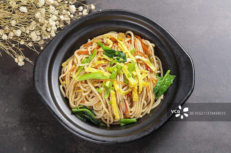 一盘快餐炒米线摆放在黑色背景上图片素材