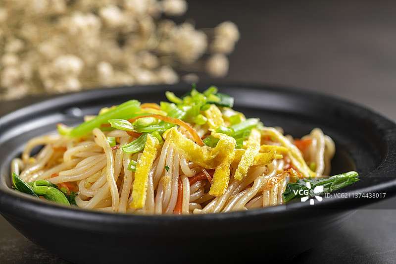 一盘快餐炒米线摆放在黑色背景上图片素材