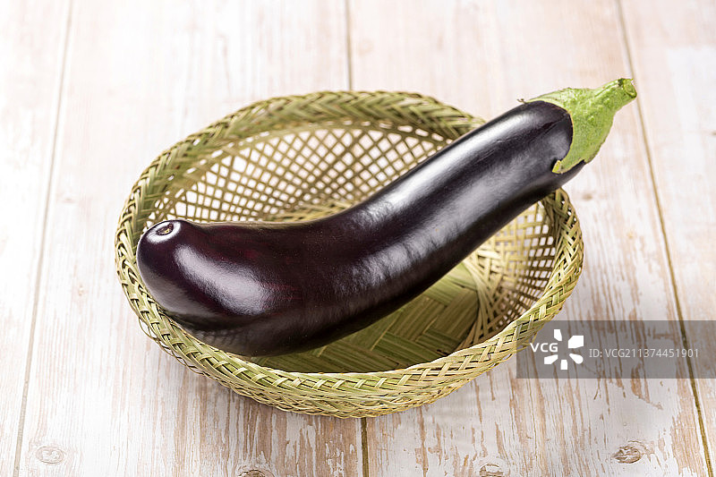一簸箕紫红长茄子特写木桌面背景图片素材