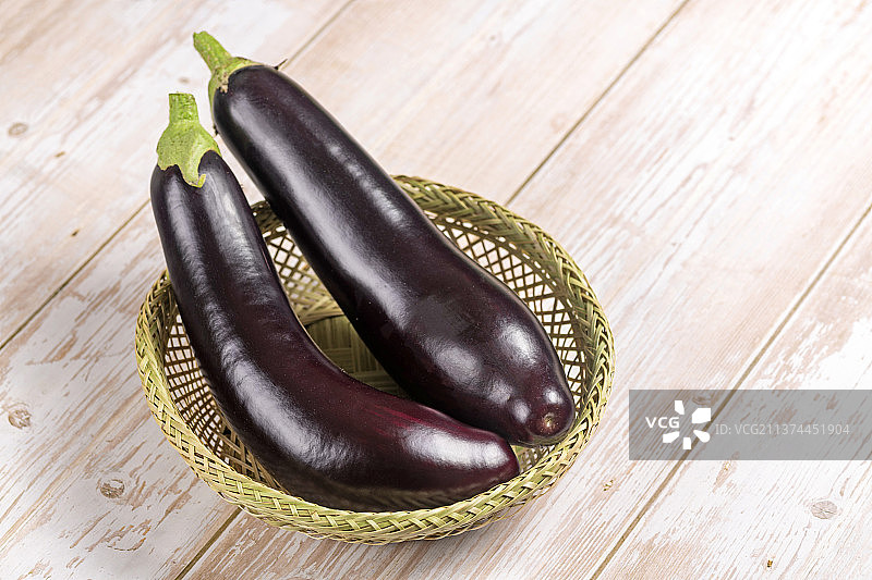 一簸箕紫红长茄子特写木桌面背景图片素材