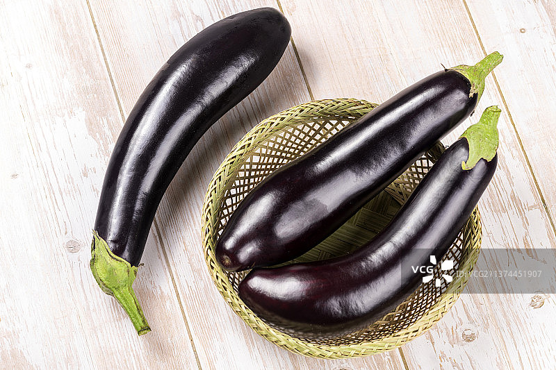 一簸箕紫红长茄子特写木桌面背景图片素材