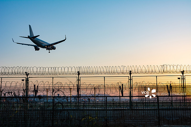大连南方航空一架客机迎着落日降落机场护栏网图片素材