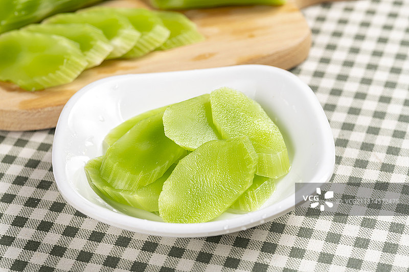 一盘莴笋片和正在切片的莴笋特写图片素材