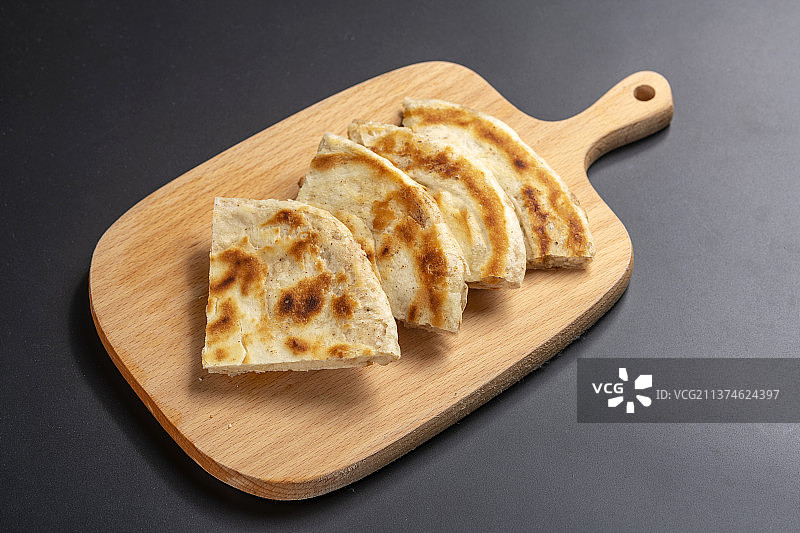 切开的发面饼摆放在木砧板上与整张发面饼特写黑色背景图片素材