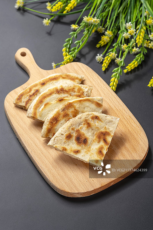 切开的发面饼摆放在木砧板上与整张发面饼特写黑色背景图片素材