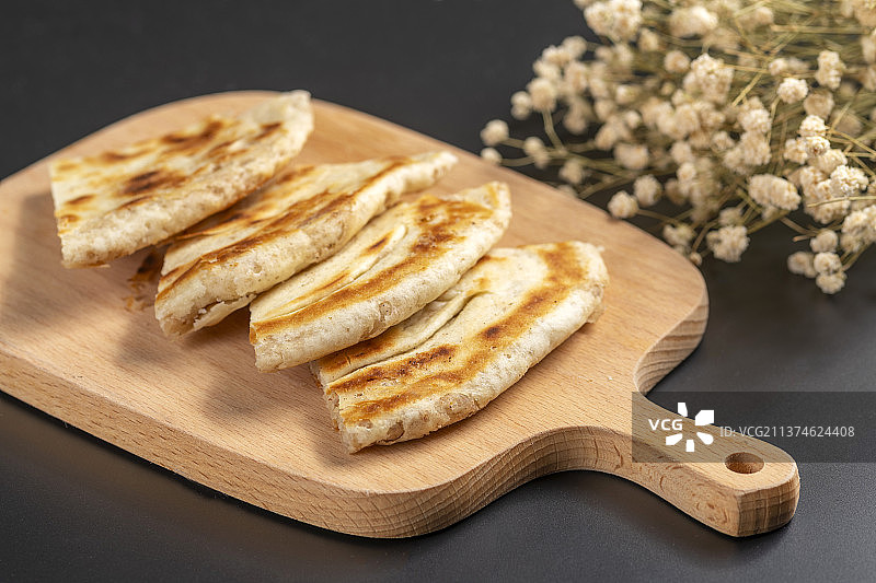 切开的发面饼摆放在木砧板上与整张发面饼特写黑色背景图片素材