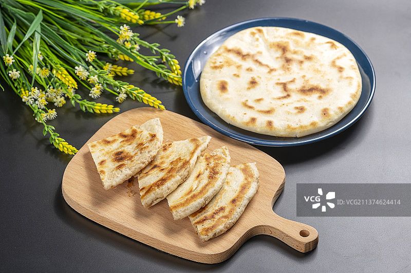 切开的发面饼摆放在木砧板上与整张发面饼特写黑色背景图片素材