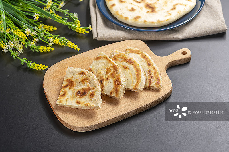 切开的发面饼摆放在木砧板上与整张发面饼特写黑色背景图片素材