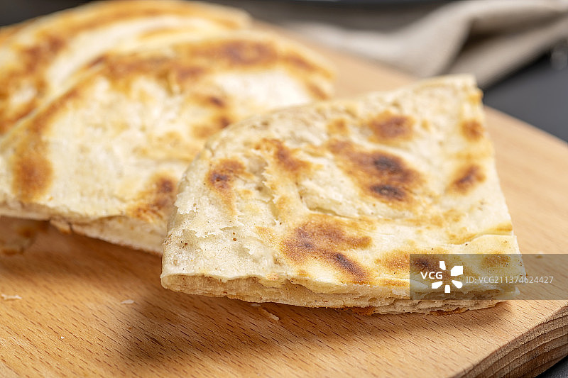 切开的发面饼摆放在木砧板上与整张发面饼特写黑色背景图片素材