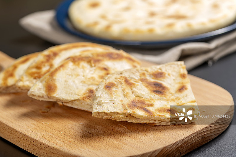 切开的发面饼摆放在木砧板上与整张发面饼特写黑色背景图片素材