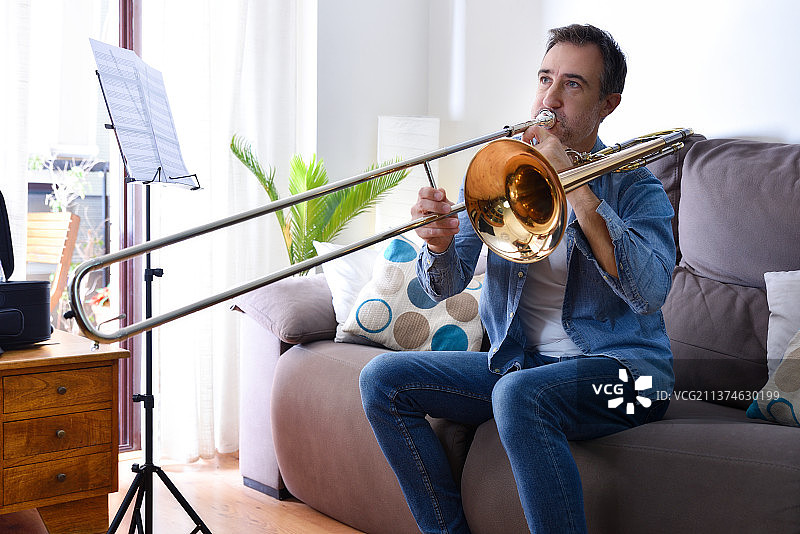 男子在家中客厅热情地练习长号图片素材