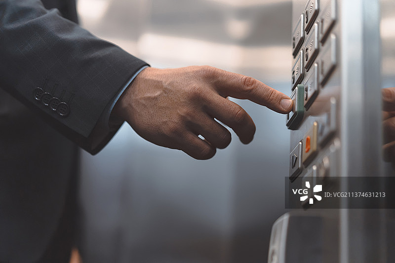 穿商务套装的男人按下电梯按钮图片素材