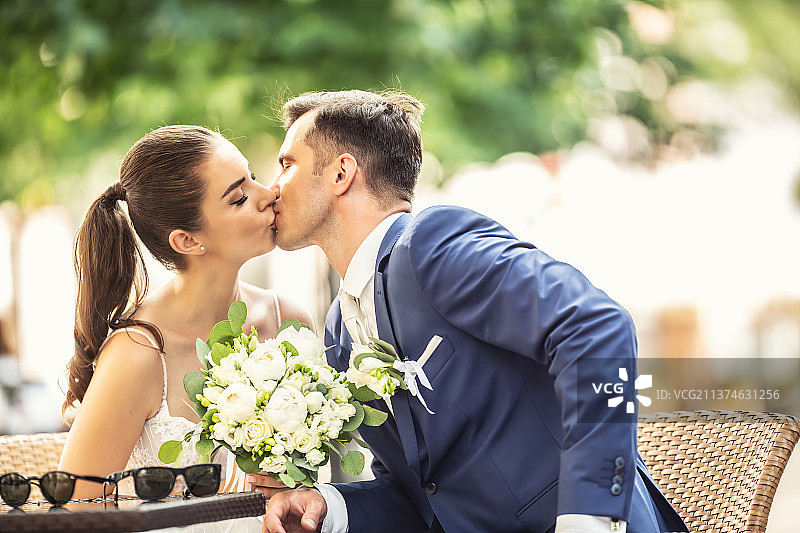 快乐的夫妇在婚礼后坐着亲吻图片素材