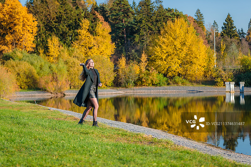 长发女子在秋天的公园里散步并抛掷物品图片素材