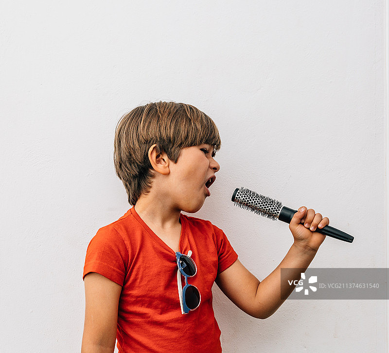 白人金发男孩假装用梳子唱歌图片素材