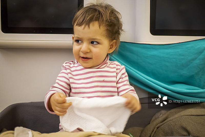 快乐可爱的小女婴坐在婴儿摇篮里图片素材