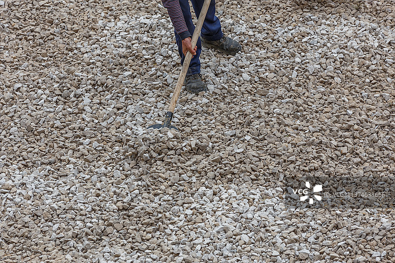 建筑工人在道路施工期间铲白色碎石图片素材