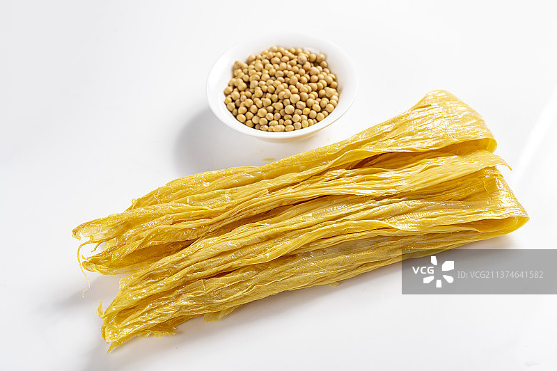 一捆干腐竹与一盘泡发腐竹及黄豆特写图片素材