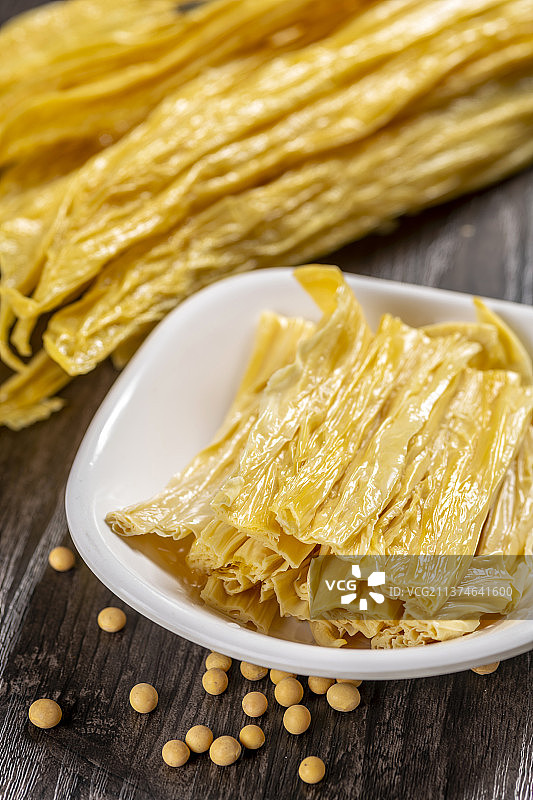 一捆干腐竹与一盘泡发腐竹及黄豆特写图片素材