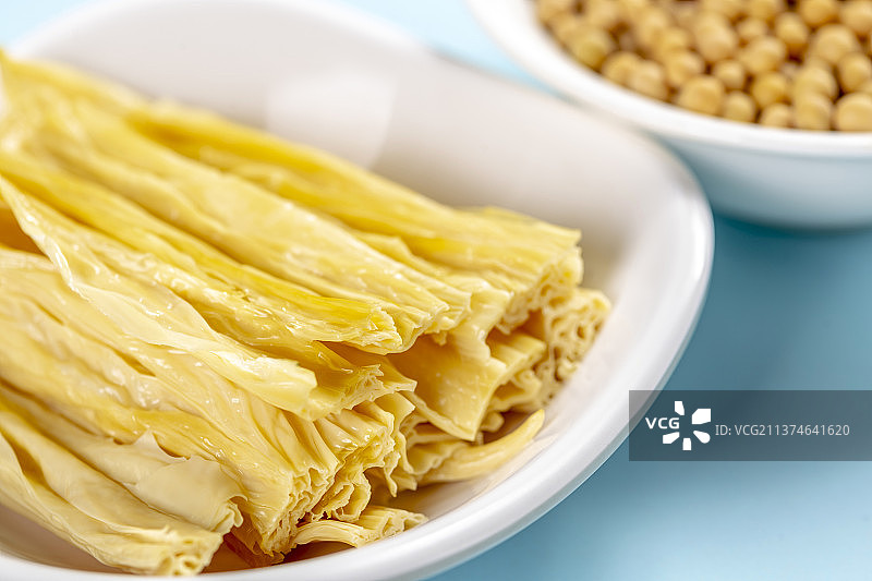 一捆干腐竹与一盘泡发腐竹及黄豆特写图片素材