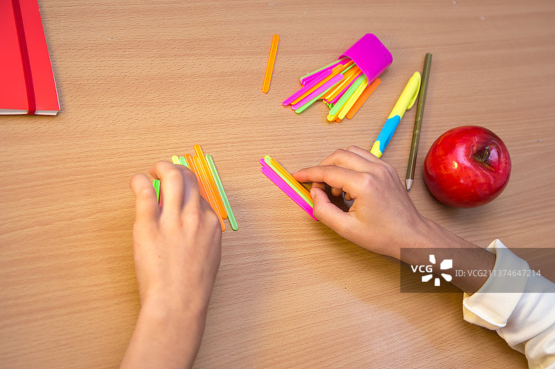 在书桌前用木棍学习算术的学生图片素材