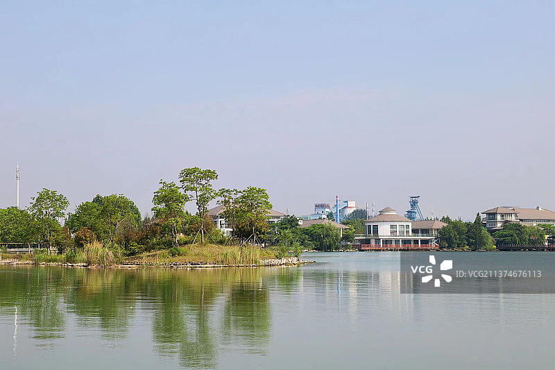 开阔的水面，倒影的垂柳，明净的天空，岸边的花草， 远处的建筑构成一幅美丽的生态画卷。图片素材