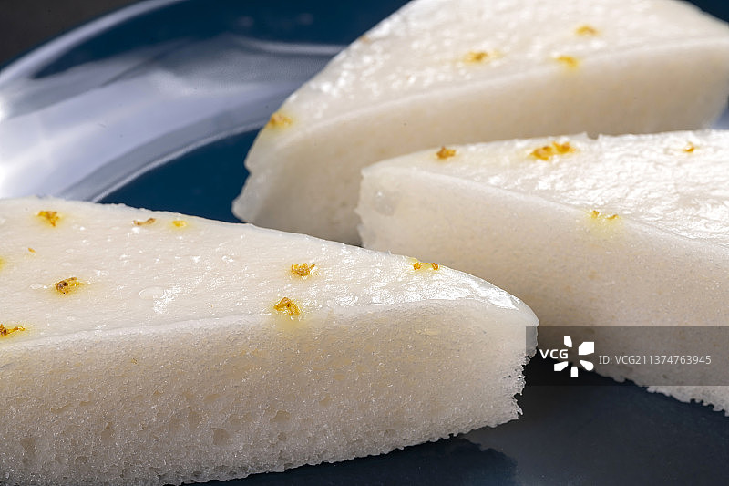 一盘桂花糕与茶水摆放在黑色背景上图片素材