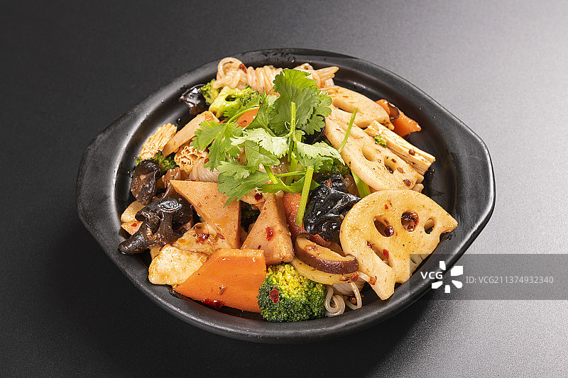 一盘麻辣香锅与一碗米饭调料特写黑色背景图片素材