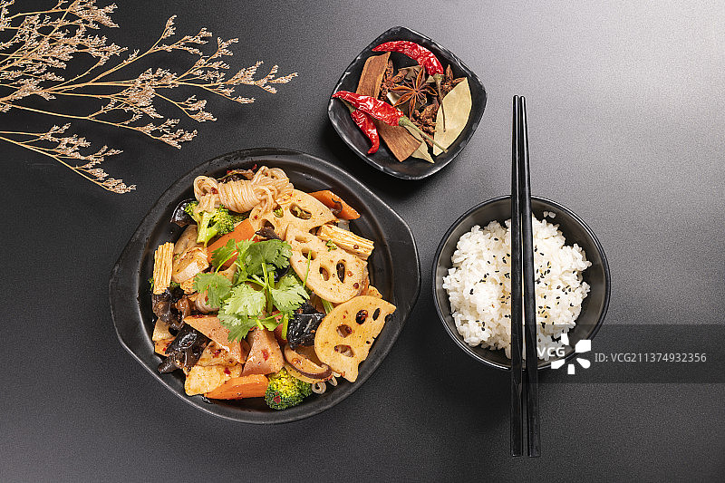 一盘麻辣香锅与一碗米饭调料特写黑色背景图片素材