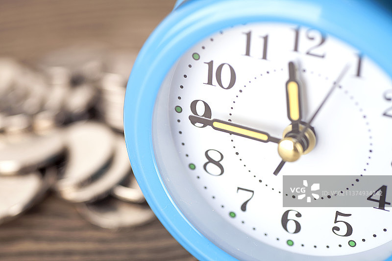 特写闹钟表盘和模糊的硬币背景图片素材