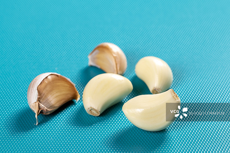 一盘剥皮大蒜特写蓝色背景图片素材