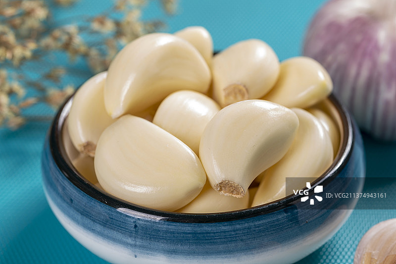 一盘剥皮大蒜特写蓝色背景图片素材