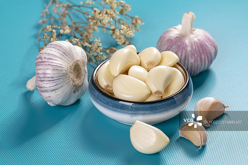 一盘剥皮大蒜特写蓝色背景图片素材