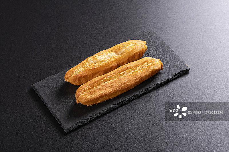 传统早餐一盘油条特写黑色背景图片素材