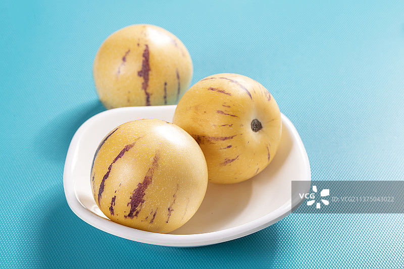 一盘人参果与切片人参果茶水摆放在桌面上特写图片素材