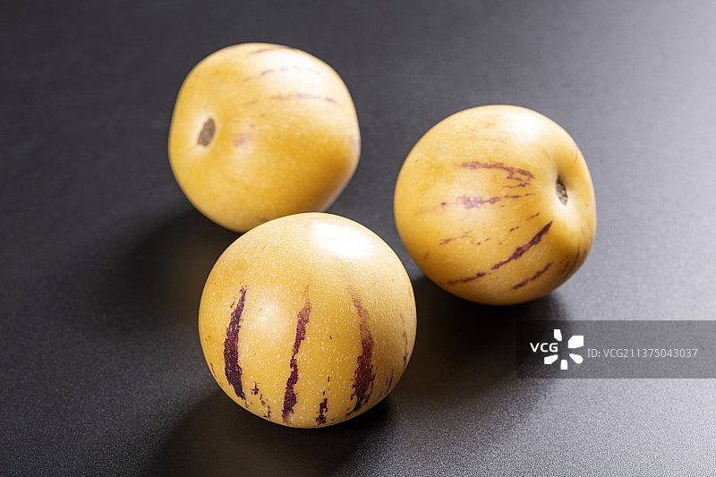 一盘人参果与切片人参果茶水摆放在桌面上特写图片素材